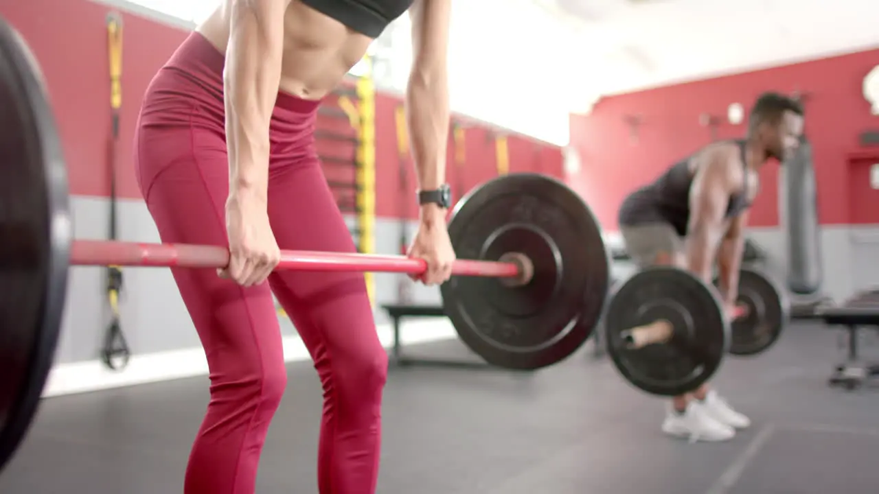 Fit young Caucasian woman and African American man at the gym lifting weights