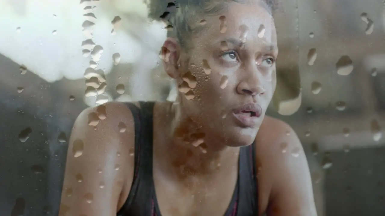 Animation of water droplets over tired african american woman recovering after exercise