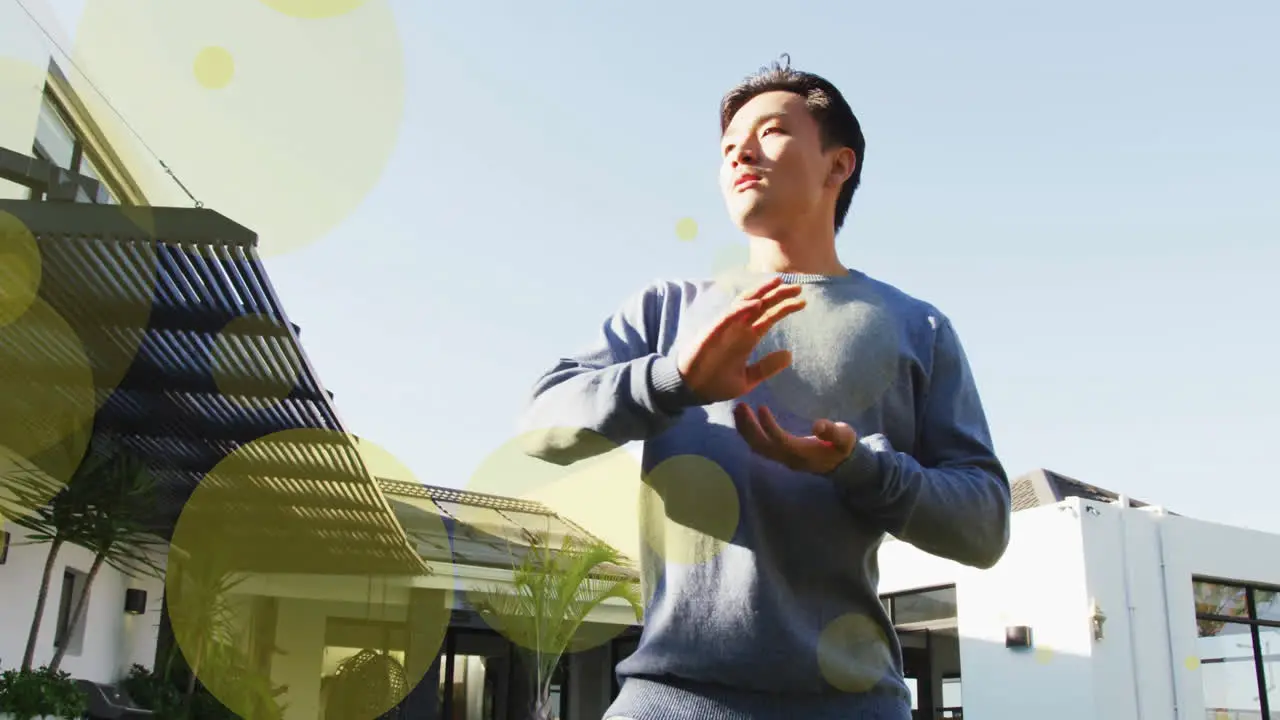 Animation of spots of light over biracial man exercising in garden at home