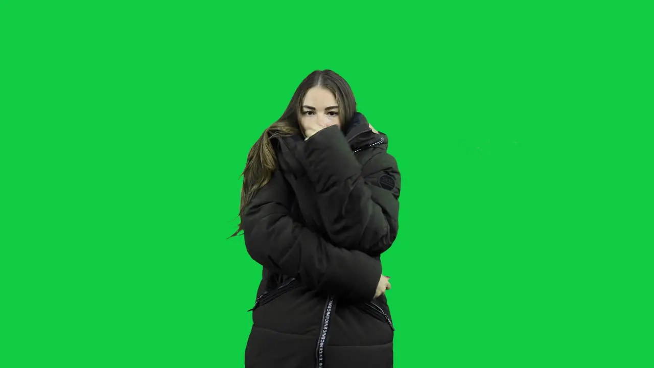 Girl freezing with warm jacket in front of a green screen