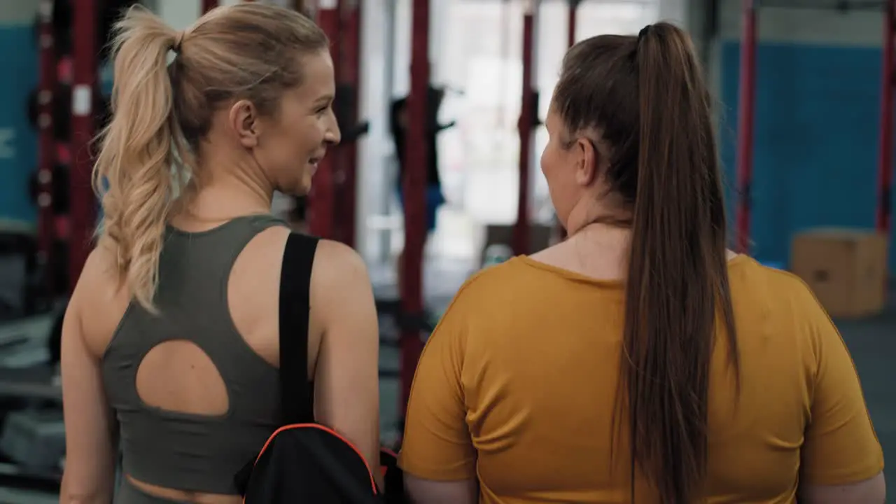 Rear view of fitness instructor walking with her customer at the gym