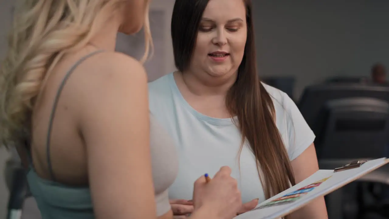 Close up of overweight talking with female trainer in the gym