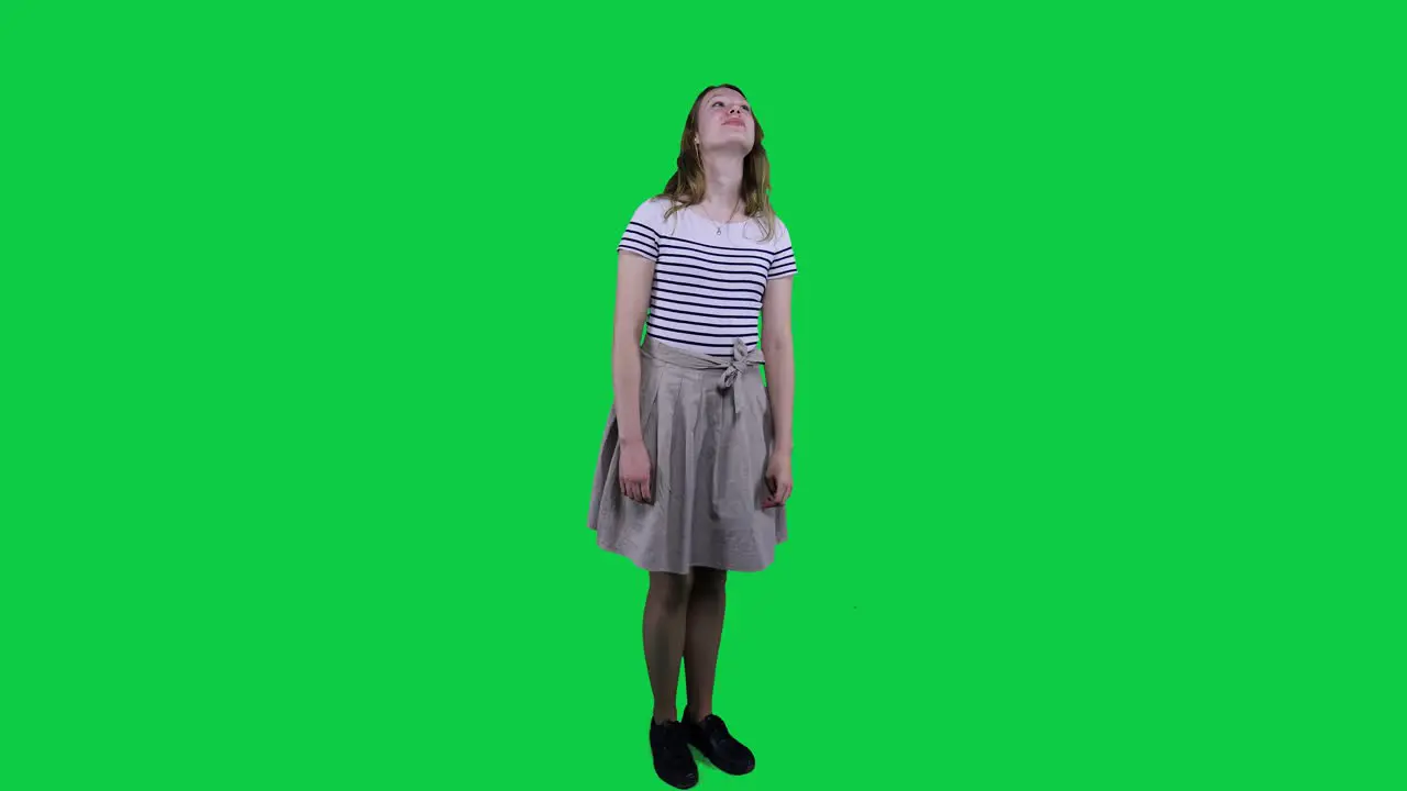 Side view teenage girl vibing to music in front of a green screen