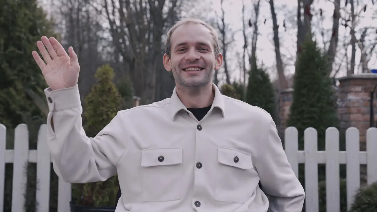 Front View Of A Man In Wheelchair Waving At Camera