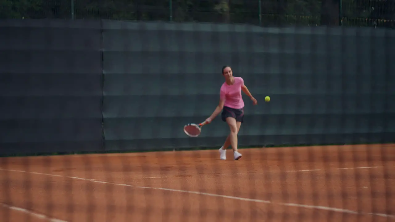 Close up of a tennis court grid in the background a woman is hitting a ball