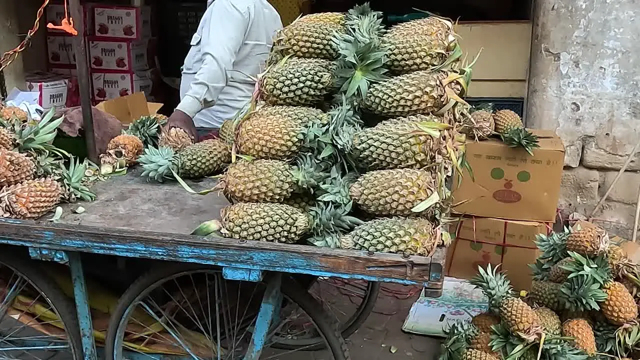 A shopkeeper is selling fresh and fresh pineapple fruit on the street road