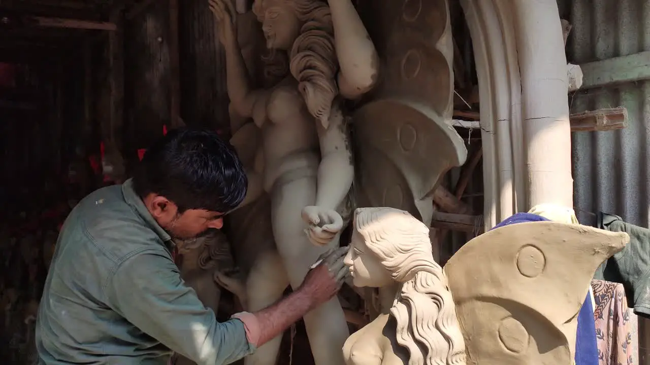 Poor Indian craftsman working on making clay idols of Gods and Goddess at daytime at workshop