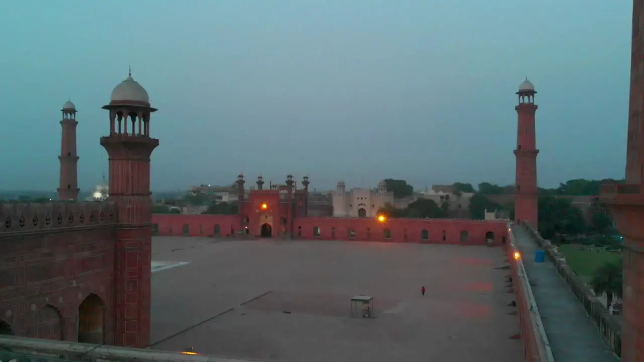 Aerial Pedestal Up Behind Red Sandstone Wall Of Badshahi Mosque In Pakistan In The Evening