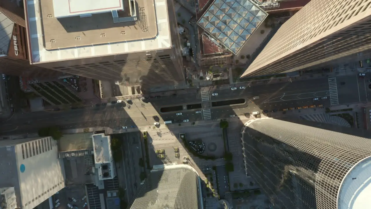 AERIAL Slow uplifting birds eye View flight over Downtown Los Angeles California Grand Avenue in beautiful Sunrise Light with view of skyscraper rooftops and car traffic passing