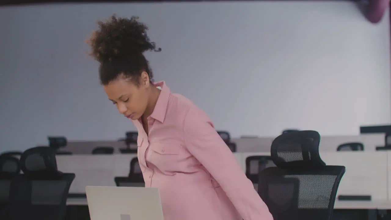 Tired Pregnant Woman Sitting At Desk In The Office