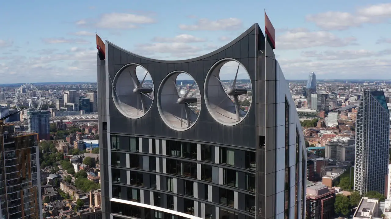 Pull back shot of top of Strata skyscraper Modern design tall apartment building with three wind turbines integrated in construction London UK