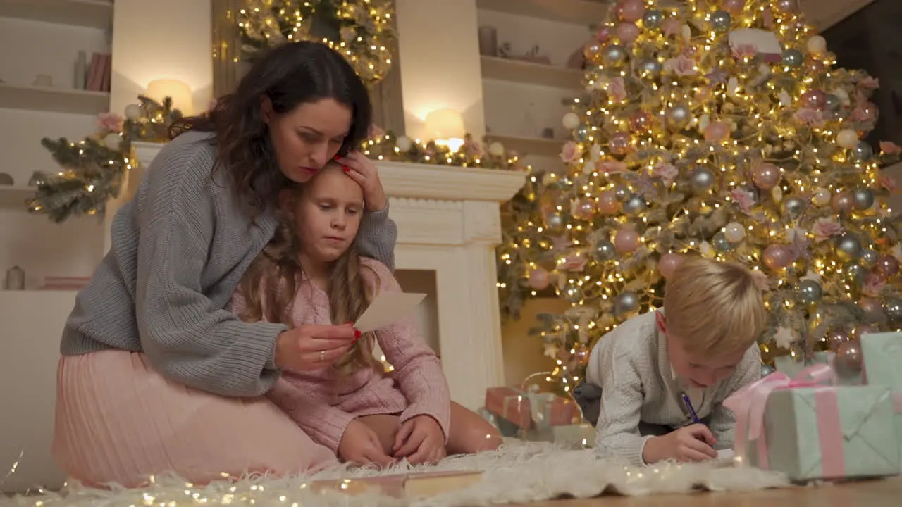 Niño Y Niña Escriben Y Leen Una Carta Con Su Madre En El Suelo Junto A Los Regalos Y El árbol De Navidad