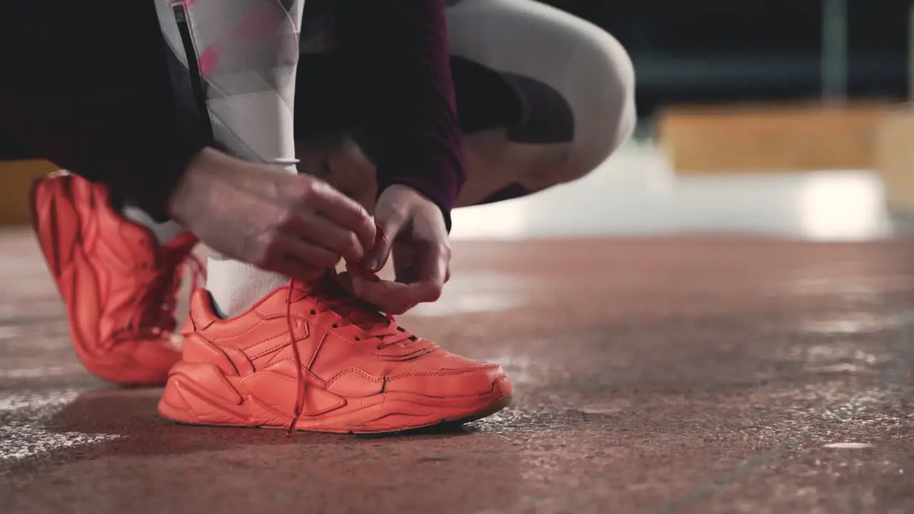 Primer Plano De Una Deportista Atándose Los Cordones Durante Su Sesión De Carrera En El Parque Por La Noche