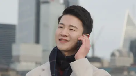 Junger Asiatischer Geschäftsmann Der Am Handy Mit Der Skyline Der Stadt London Im Hintergrund Spricht 1