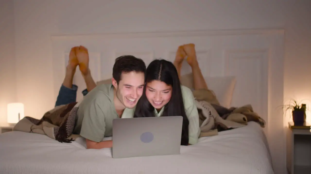 Pareja Viendo Una Película Cómica En Una Laptop Acostada En La Cama En Casa