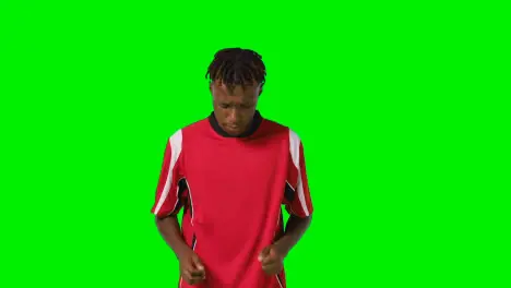 Studio Shot Of Young Male Footballer Warming Up With Exercises Before Game Against Green Screen