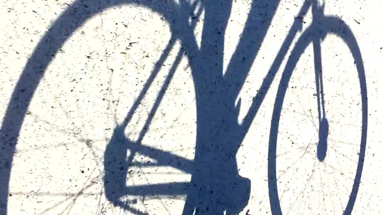 Shadow of a man cycling along a dirt track in bright sunshine