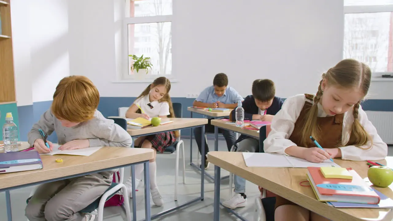 Multiethnische Gruppe Von Studenten Die An Schreibtischen Im Englischen Klassenzimmer Sitzen Und In Ihre Notizbücher Schreiben