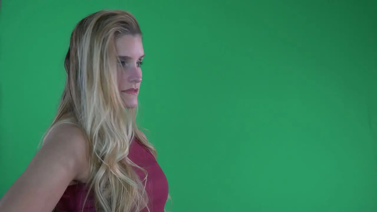 Beautiful Blonde Woman in Red Tank Top Flips Hair and Poses For Camera in Front of Green Screen