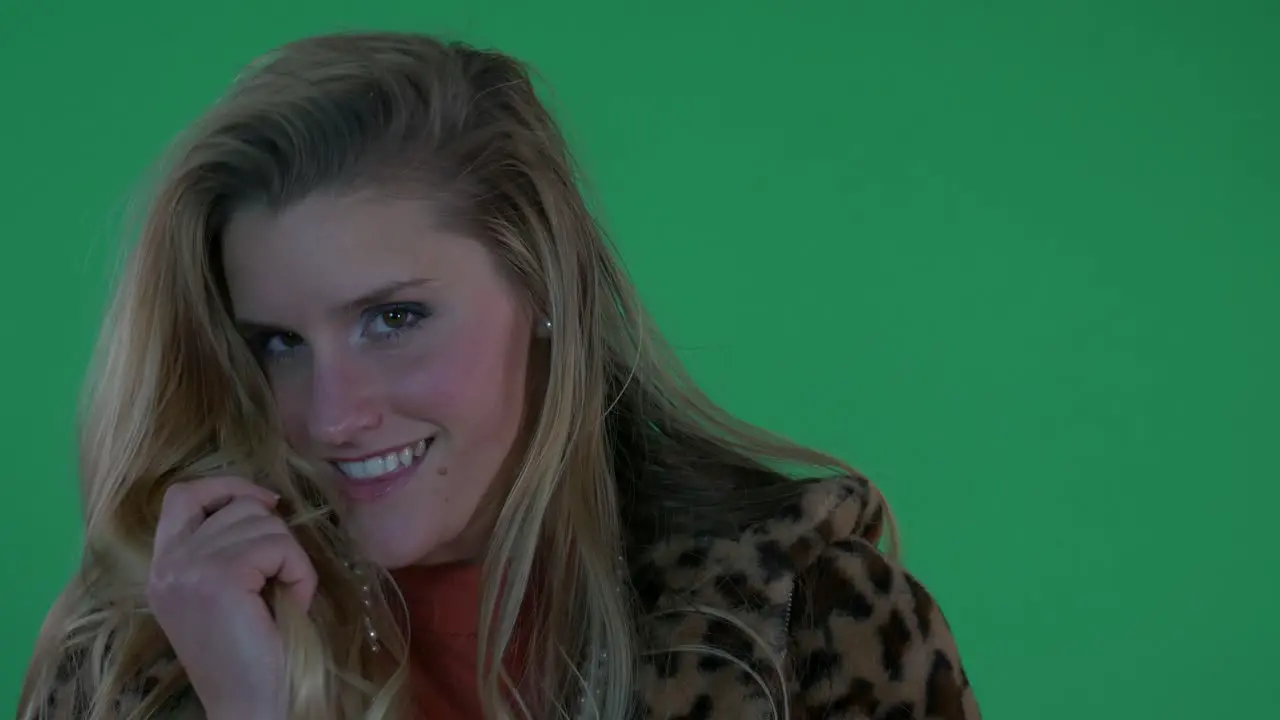 Beautiful Blonde Woman in Leopard Print Coat Smiles at the Camera in Front of Green Screen