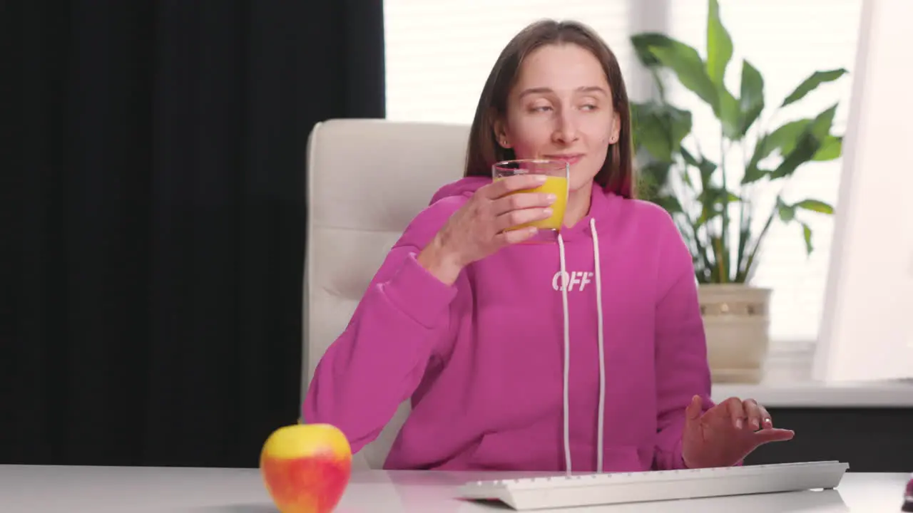 Mujer Joven Bebiendo Un Jugo De Naranja Saludable Mientras Usa Una Computadora De Escritorio En La Oficina