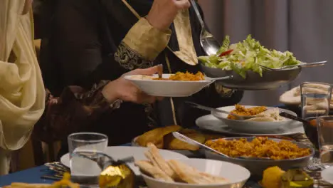 Primer Plano De Una Familia Musulmana Sentada Alrededor De Una Mesa Con Comida Para La Comida Celebrando El Eid Que Se Sirve 1