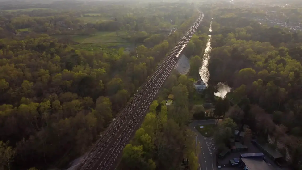 Beautiful aerial view of train travelling at sunset with forest and fields