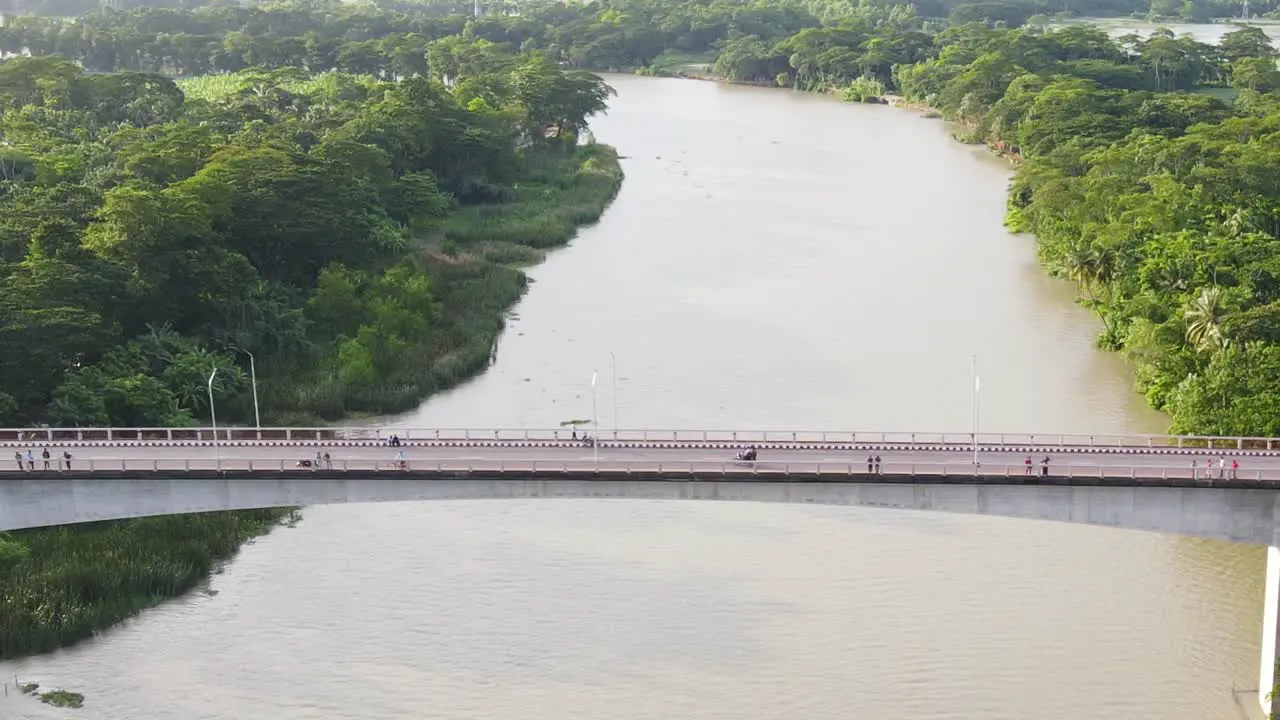 Aerial follow motorbike crossing bridge nature landscape river and forest Background