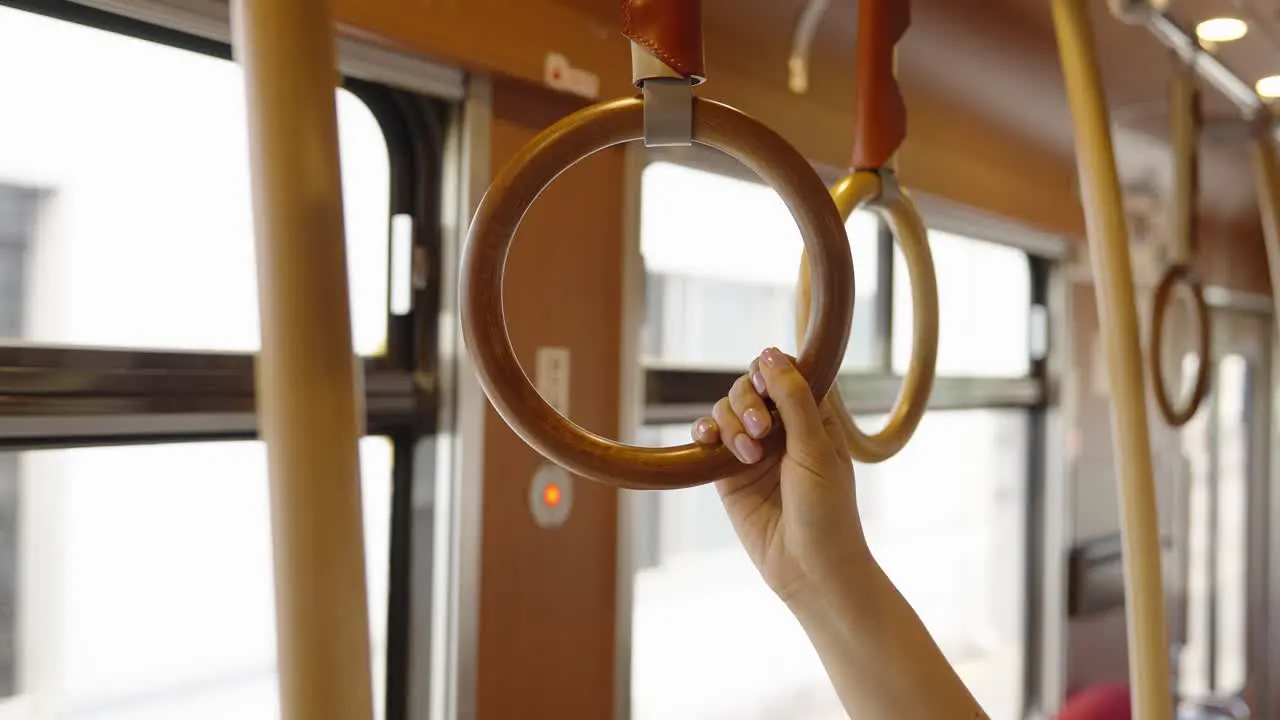 Woman grabs onto round hanging handle on Kagoshima tram