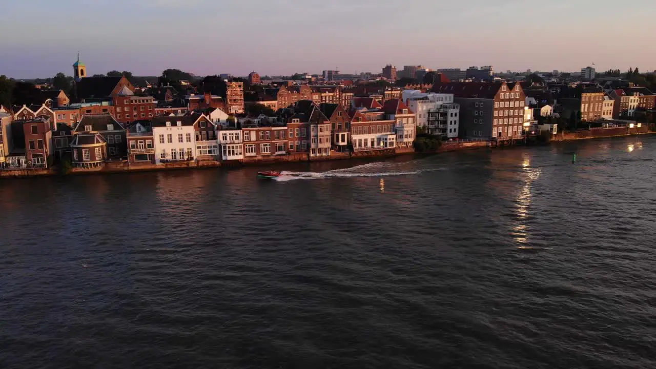 Boat Speeds Down The River Near The Cityscape Of Dordrecht In Netherlands