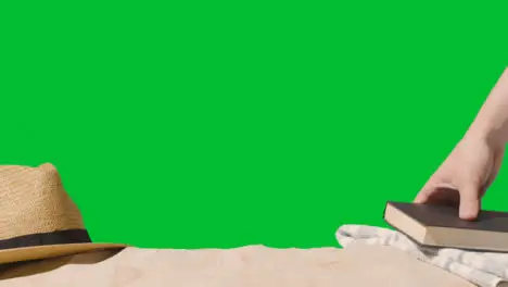 Summer Holiday Concept Of Book Sun Hat Beach Towel On Sand Against Green Screen