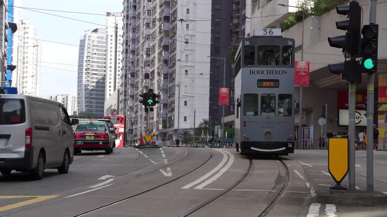 Cinematic shot of Hong Kong city busy streets with traditional double-decker Tramway Car Bus and people with skyline buildings in the background