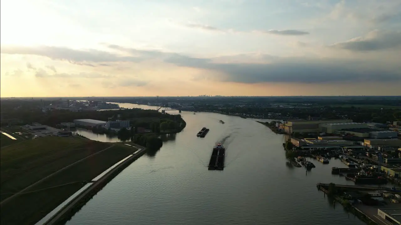 Aerial view of powerful ship pushing four barges on river along industrial zone