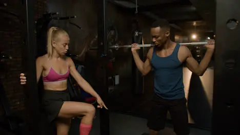 Caucasian female monitor and an athletic african american man in the gym