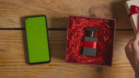 Overhead Shot Of Romantic Valentines Present Of Perfume Gift Wrapped In Box Next To Green Screen Mobile Phone 