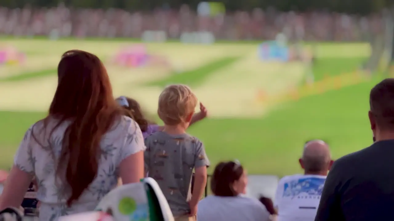 Close up behind a family cheering at a show at an outdoor stadium event