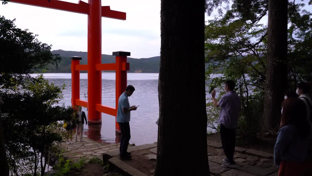 Crowd of people wearing facemasks gathered at Hakone Shrine Torii gate to take pictures