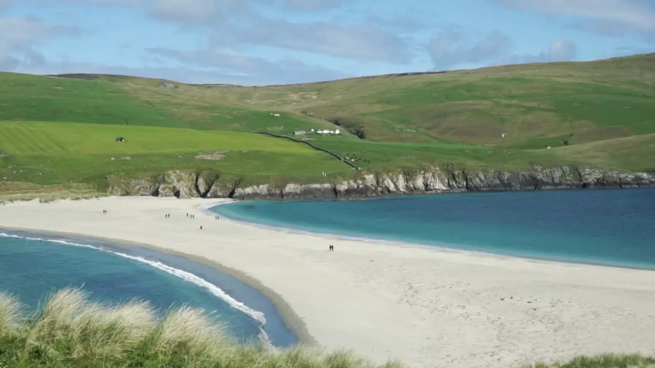 People crossing the St Ninian's Isle sand bar at low tide on a clear day