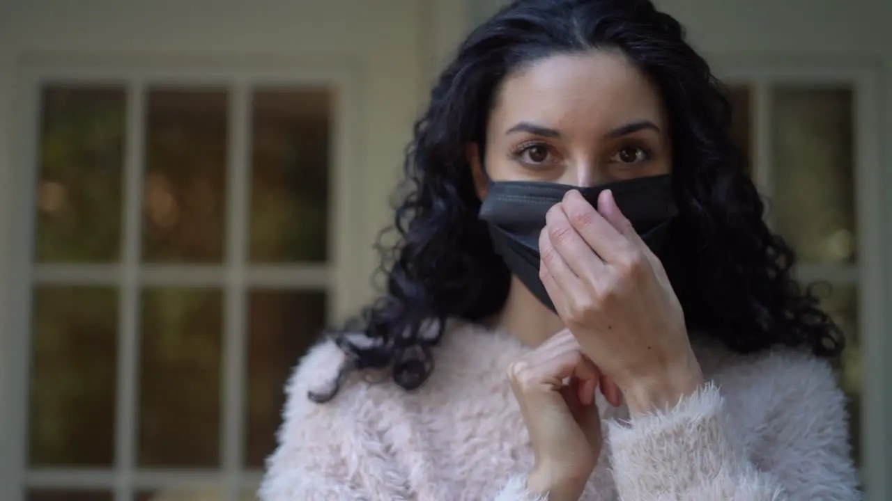 Young Latina woman makes sure her face mask fit properly over her nose isolated