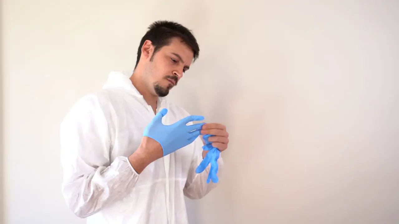 Doctor in PPE suit putting on blue latex gloves