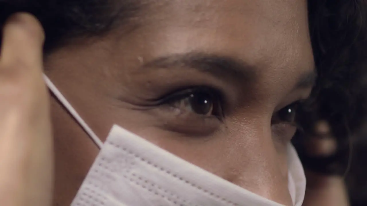 Attractive Latina or black mixed race woman putting on a face mask isolated close up