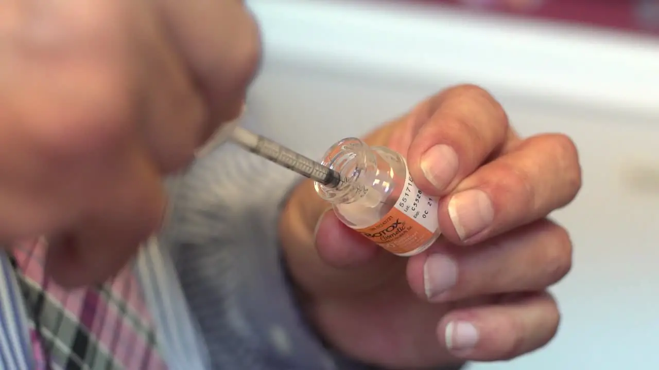 Hands Of A Plastic Surgeon Drawing Botulinum Toxin From A Vial With Syringe