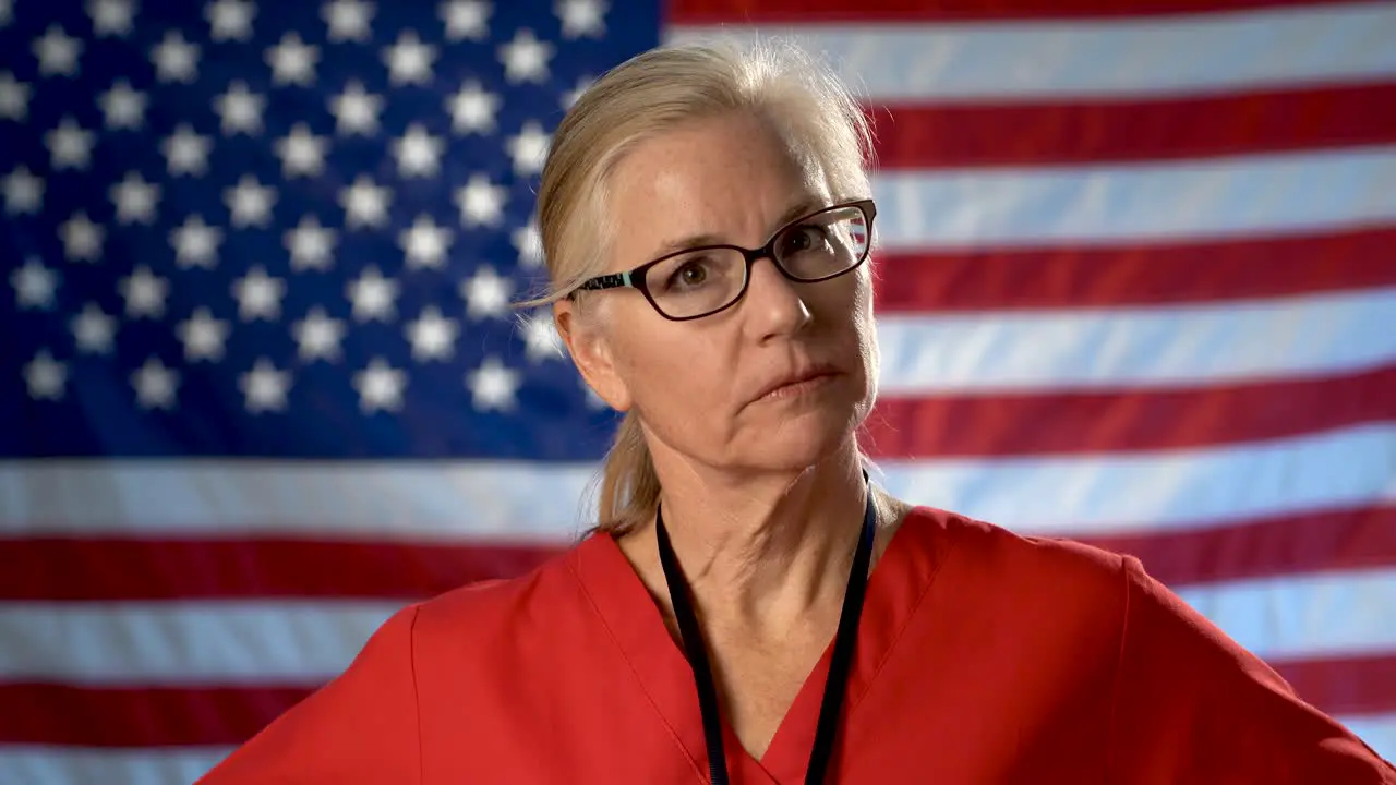 Portrait of a nurse walking from US flag to foreground and showing a seriousness and disapproval