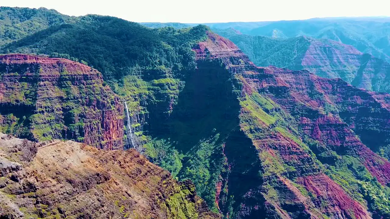 HD Hawaii Kauai slow motion boom up and slight pan left to right from a few pieces of long grass in lower left to Waimea Canyon with a waterfall in distance