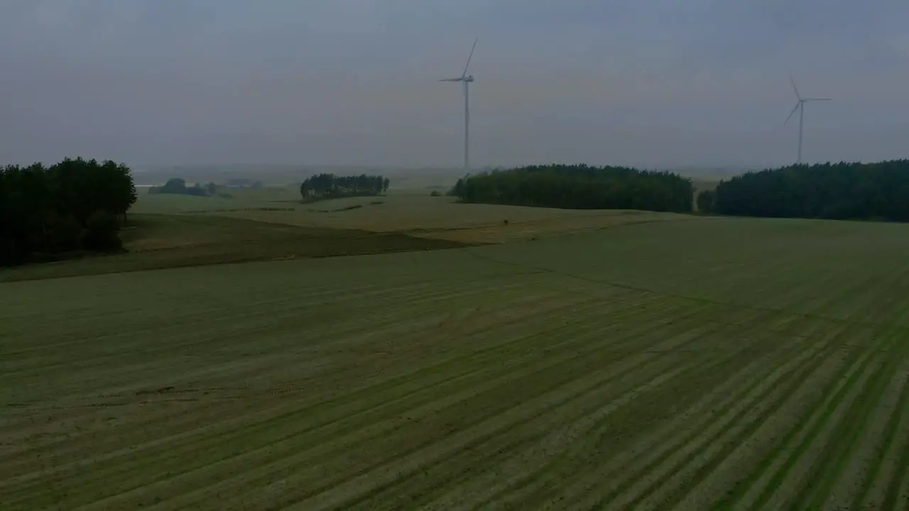 Aerial footage in foggy morning at the wind farm windmills close together in the field