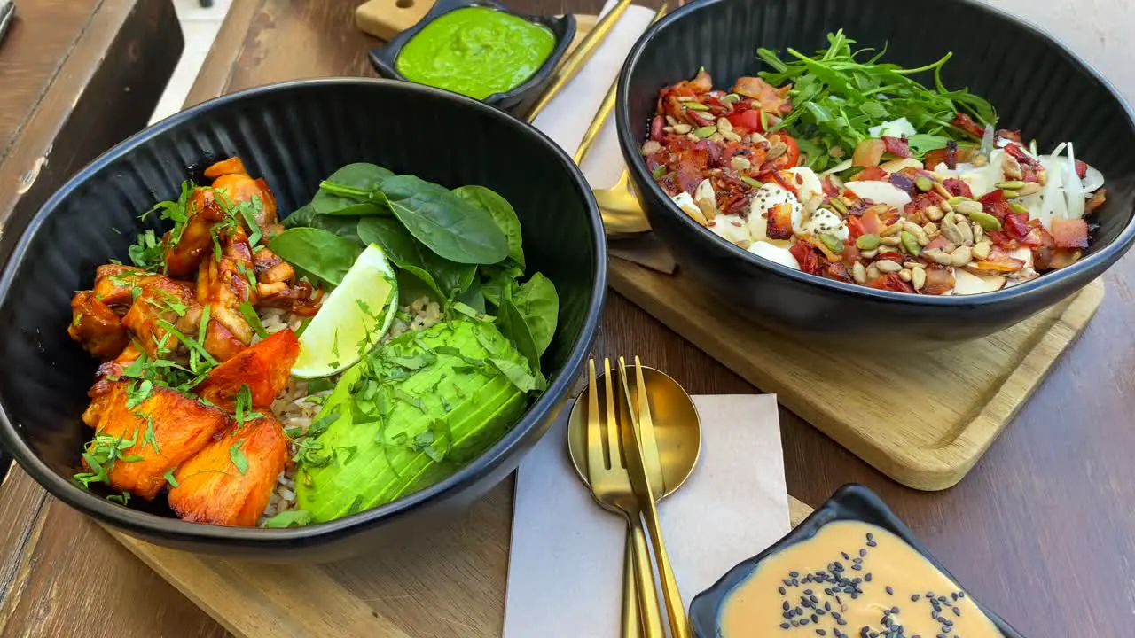 Tasty healthy green salads in a bowl with chicken avocado lettuce crispy bacon and microgreens with salad dressing lunch time 4K shot