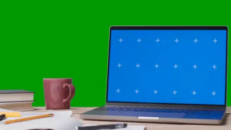 Blue Screen Laptop With Books On Table With Green Screen Background 1