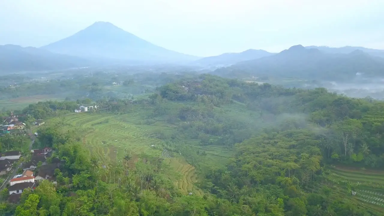 Aerial panning shot of hilly tropical landscape and mountains in Indonesia