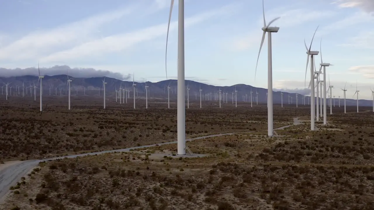 Wind turbine farm rising aerial view across many turbines on vast mountain landscape