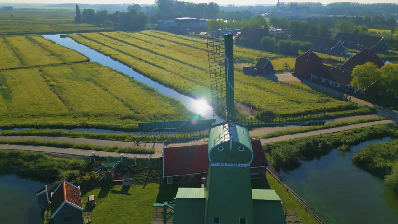 Fixed shot of sails of windmill in backlight with a reflection of sun in polder